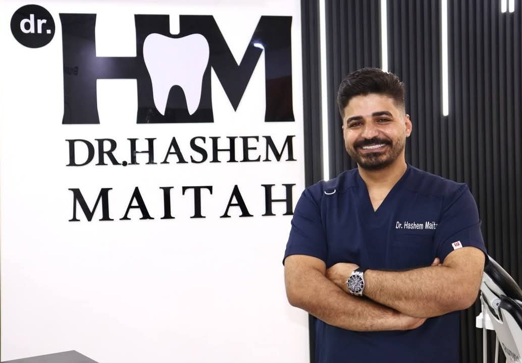 Dr. Hashem Maitah standing next to clinic logo